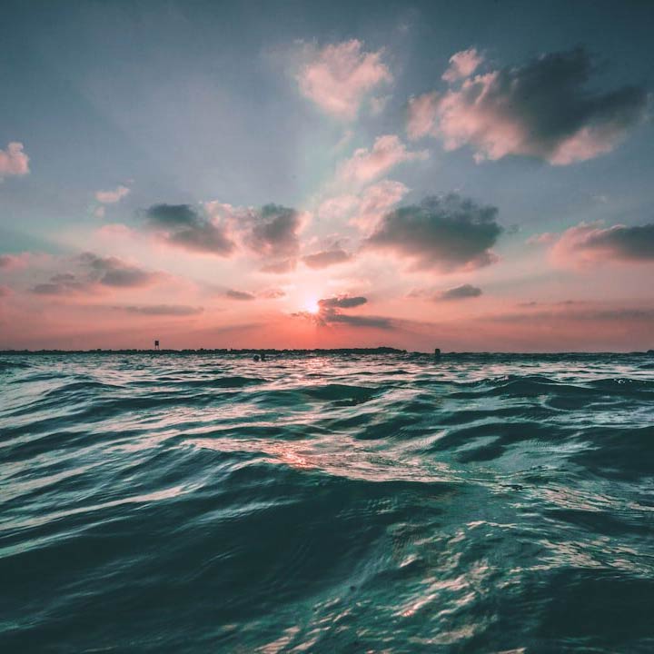 Ocean waves and a an orange sunset in the background.